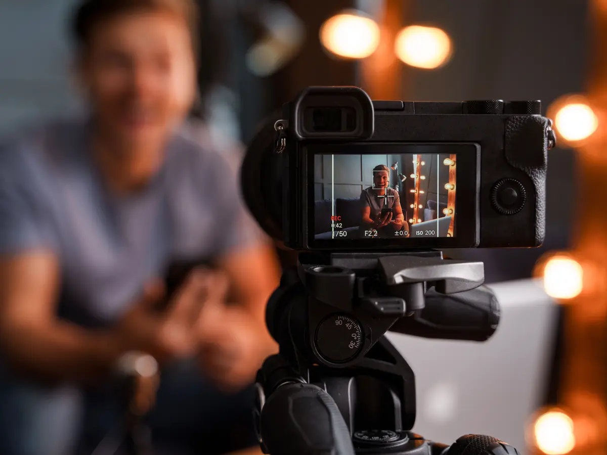 Camera on a tripod recording a creator speaking in a studio