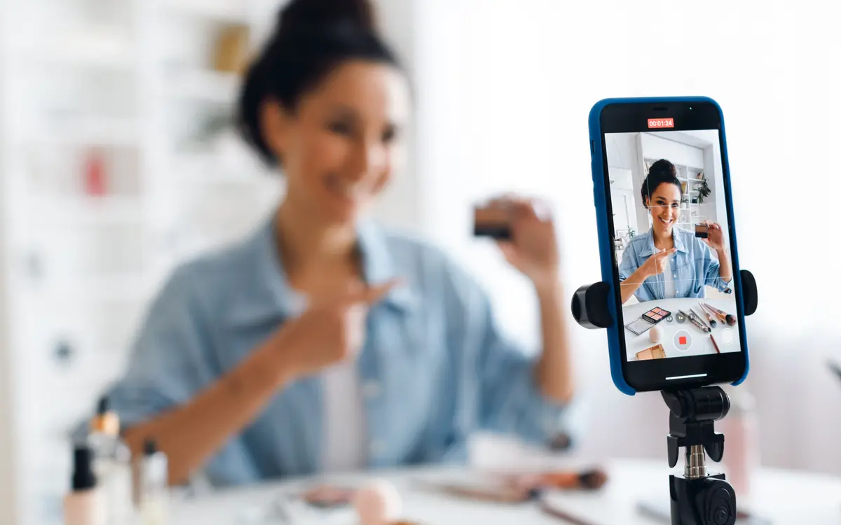 Creatorin nimmt mit dem Smartphone auf einem Stativ ein Produktvideo auf