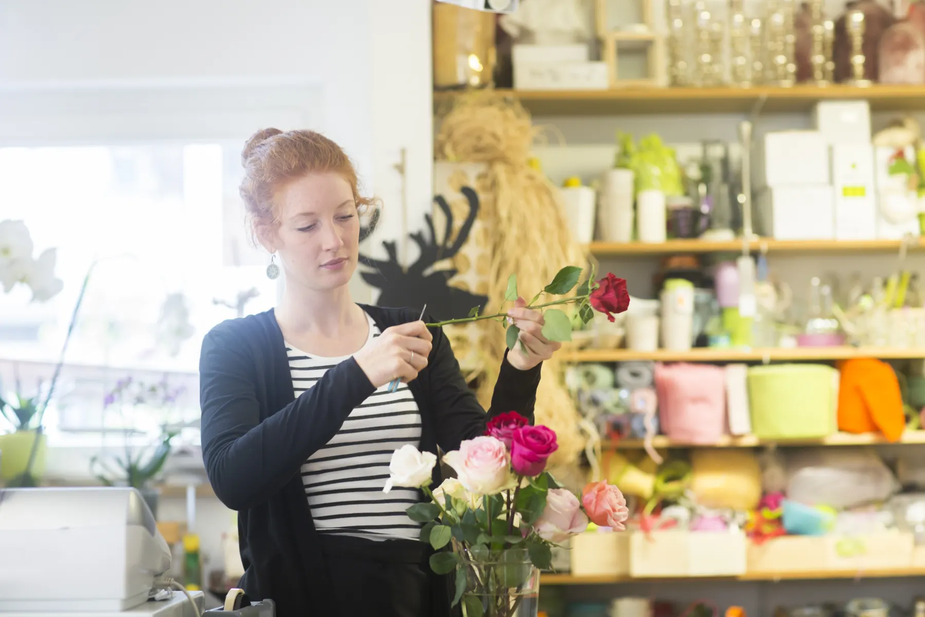 Floristin arrangiert Blumen in ihrem Geschäft